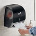 A person using a Scott Slimroll wall mount automatic paper towel dispenser to dry their hands.