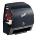 A Scotts black wall mount paper towel dispenser.