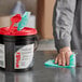 A person using a WypAll heavy-duty pre-moistened wiper to clean a surface in a professional kitchen.