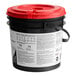 A black bucket with a red lid containing WypAll PowerClean ProScrub pre-moistened wipes.