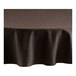 A chocolate brown round cloth table cover with a hemmed edge on a table with a white surface.