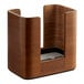 A Tork walnut wood interfold tabletop napkin dispenser on a table with a white surface.