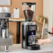 A woman using a Mahlkonig E65W espresso grinder on a counter in a coffee shop.