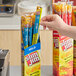 A hand holding a blue box of Slim Jim meat sticks.