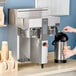 A person pouring coffee into a Fetco commercial coffee maker.