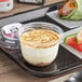 A white Our Specialty Treat Shop French-Style Cheesecake Mousse Parfait container on a tray.