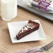 An individually wrapped HERSHEY'S chocolate chip brownie slice on a plate with a fork next to a glass of milk.