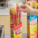 A hand holding a box of Slim Jim Original meat sticks.