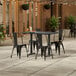 A Lancaster Table and Seating rectangular table with black chairs on an outdoor patio.