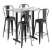 A Lancaster Table & Seating rectangular white marble table with black barstools around it.