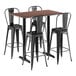 A Lancaster Table & Seating rectangular walnut bar height table with black metal legs and three black bar stools.