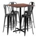 A Lancaster Table & Seating bar height table with black metal and textured walnut top with four black metal bar stools.