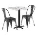 A Lancaster Table & Seating Excalibur table with 2 black chairs.