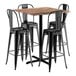 A Lancaster Table & Seating Excalibur bar height table with a textured wood top and four black metal barstools with black backs.