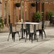 A Lancaster Table and Seating rectangular table and 4 black metal chairs on a patio.