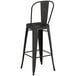 A Lancaster Table & Seating black metal bar height table with 2 black metal barstools with a backrest.