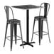 A Lancaster Table & Seating bar height table with a black top and two black bar stools.