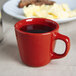 A red Tuxton Colorado China tall cup with a drink on a table.