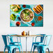 A table with blue chairs and a Vietnamese feast canvas on it.