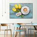 A blue chair next to a white table with a cup of coffee and yellow tulips on it.