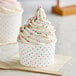 A Choice polka dot paper cup filled with ice cream and sprinkles.