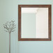 A BrandtWorks mocha walnut brown finish mirror on a wall.