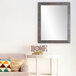 A BrandtWorks Industrial Lauralee Rust Finish Mirror mounted on a wall above a couch.