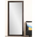 A BrandtWorks large black mirror with a black frame leaning against a white wall.