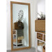 A BrandtWorks blonde barn finish wall mirror in a white room with a basket of plants.