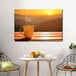 A coffee cup on a table with a view of the sunset in a room with Elephant Stock Sunset Coffee Canvas Wall Art.