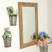 A BrandtWorks Blonde Barn Finish mirror with a metal container of flowers on the wall.