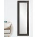 A long rectangular BrandtWorks black mirror on a wall next to a couch.