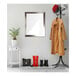 A BrandtWorks silver mirror hanging above a white coat rack with a black bag and potted plant.