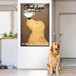 A golden retriever sitting in front of a poster with a dog holding a cup of coffee on its nose.