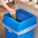 A hand putting a paper cup into a blue Lavex square trash can.