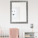 A BrandtWorks vintage silver mirror in a white baby's nursery above a white crib.