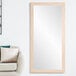 A BrandtWorks natural grain finish mirror on a white wall above a white couch.