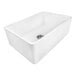 A Ruvati white fireclay farmhouse sink with a silver drain.