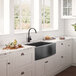 A kitchen with white cabinets and a Ruvati matte black gunmetal stainless steel farmhouse sink.