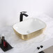 A Ruvati rectangular white porcelain sink with decorative gold accents on a counter.