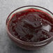 A bowl of Crofter's Organic Concord Grape Jelly on a table with a spoon in it.