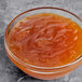 A bowl of apricot preserves on a gray surface.