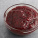 A bowl of Crofter's Organic Raspberry Preserves on a gray surface.