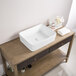 A Ruvati white rectangular above-counter sink on a wood table.