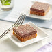 Two square brown and white Nats Rawline chocolate dessert squares on a plate.