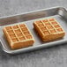 Two Le Chic Patissier chocolate-filled Belgian waffles on a baking pan.