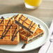 A Le Chic Patissier chocolate-filled waffle on a plate with chocolate syrup.