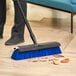 A person using a Lavex push broom with unflagged bristles to sweep the floor.
