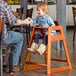 A man holding a child's hand as she sits in a Lancaster Table & Seating wooden high chair.