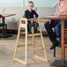A child sitting at a table in a Lancaster Table & Seating bar height high chair.